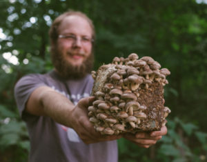 Dylan holds a block of shiitake mushrooms